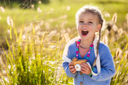Child playing with toy wooden camera pretending to be a photographer