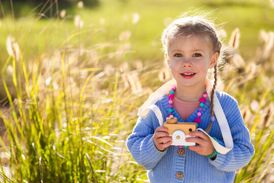 Child playing with toy wooden camera pretending to be a photographer