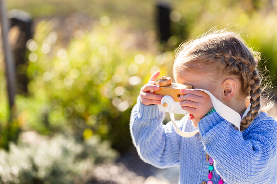 Child playing with toy wooden camera pretending to be a photographer