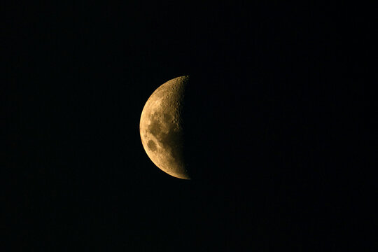 Illuminated moon surface showing visible craters and rugged textures against the black night sky