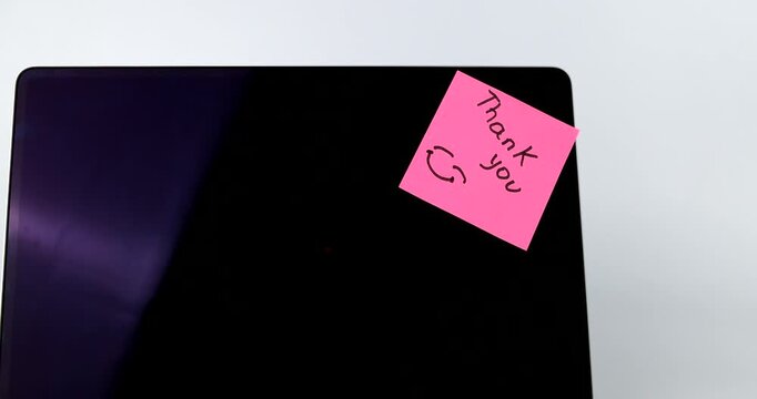 Laptop with black screen and pink Thank you sticky note on white background
