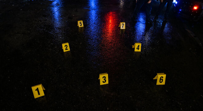 A dark street scene with numbered evidence markers at a nighttime crime scene investigation