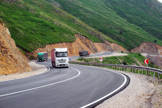 Trucks navigate sharp bend on mountain highway