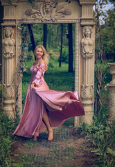 Fototapeta premium Elegant woman twirling in flowing pink dress under ornamental stone arch