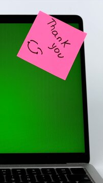 Pink sticky note with Thank you message on laptop with green screen