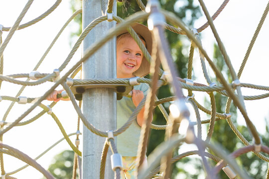 Young Australian girl climbing spider pyramid net playground equipment at park