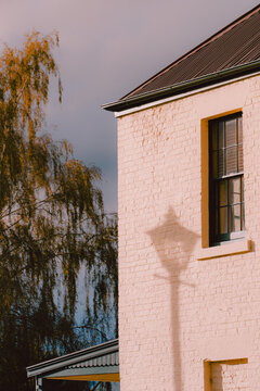 Natural light casting shadow of a streetlamp onto the pale brick wall of a heritage‑style building