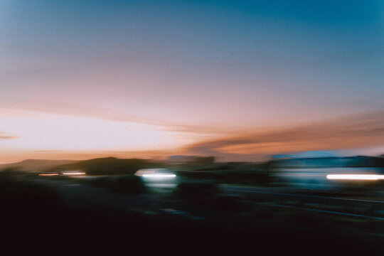 Blurred sunset road with moving cars flashing lights