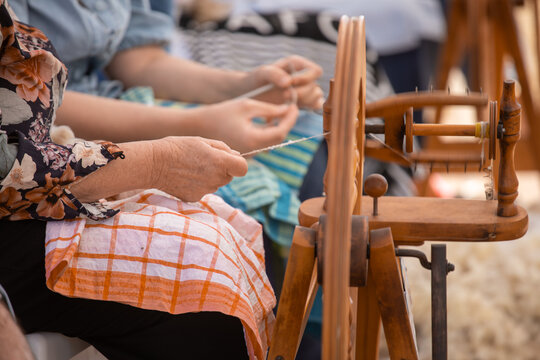 Woman spinning wool while another knits in the background