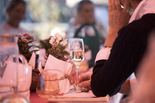 Table setting with wine glass and flowers, and people in the background