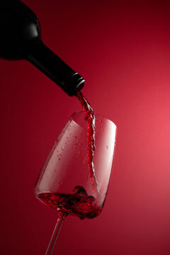 Pouring red wine from a bottle into a glass.