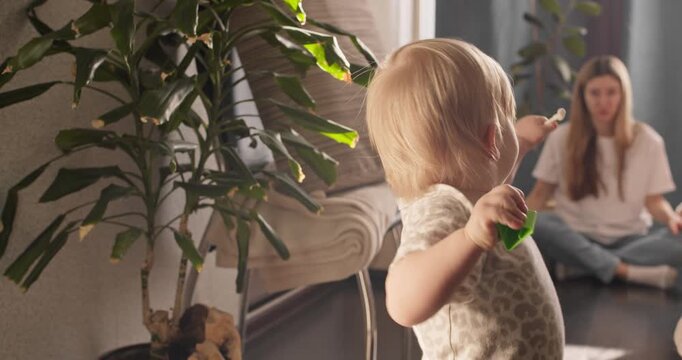 Toddler girl walking indoors with careful steps. Early walking milestone and balance practice at home