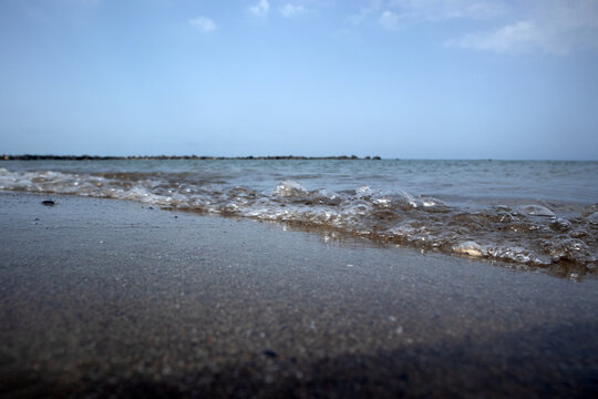 Linea di costa con onde leggere che accarezzano la sabbia bagnata in un paesaggio marino calmo e minimalista