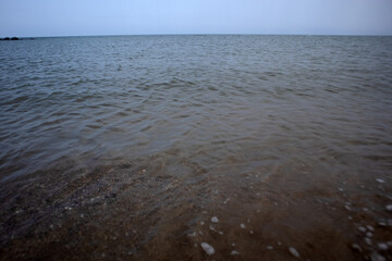 Linea di costa con onde leggere che accarezzano la sabbia bagnata in un paesaggio marino calmo e minimalista © Ilarialapreziosa