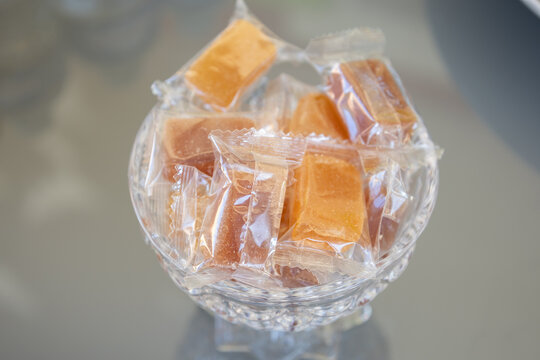 A bowl of wrapped caramel candies on a reflective surface