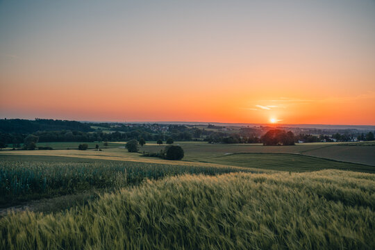 Sonnenuntergang &uuml;ber der oberschw&auml;bischen H&uuml;gellandschaft bei Schwendi und Laupheim mit Getreidefeldern im Abendlicht