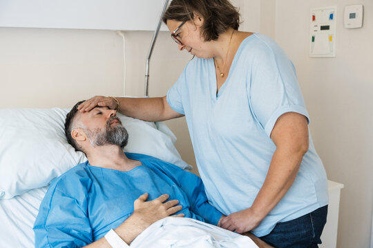 Wife showing care to sick husband in hospital
