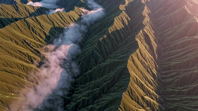 Aerial view of majestic mountain landscape. Lush green hills create stunning patterns. Clouds drift gently over peaks at sunset. Nature's beauty captivates every viewer.