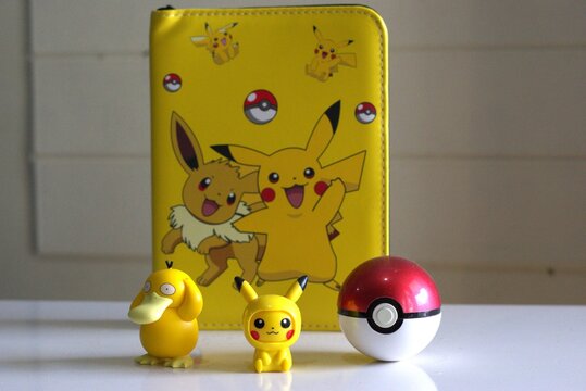 pokemon merchandise collection with figures and card album book collection on a white table