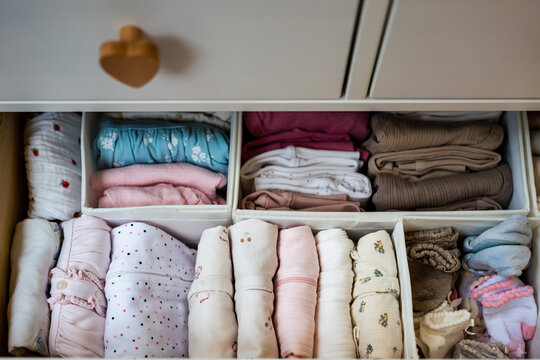 Neatly organized baby clothes arranged in dresser drawer using storage organizers, showcasing efficient wardrobe organization and newborn clothing storage at home.