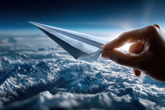 Paper airplane soaring above majestic mountain ranges and clouds during daylight