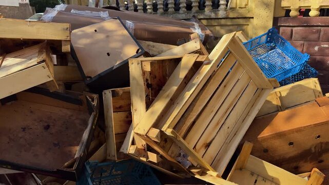 Pile of empty wooden crates, cardboard boxes and blue plastic baskets outdoors, discarded packaging and waste, recycling, disposal, clutter