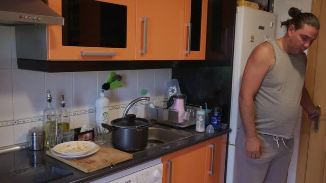 Man smelling burnt food in the kitchen