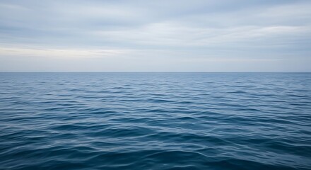 Fototapeta premium Serene ocean waves under soft cloudy sky.