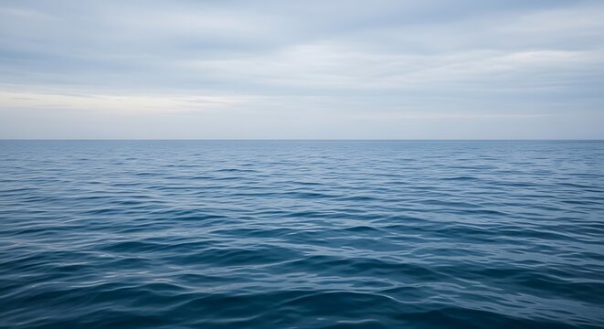 Serene ocean waves under soft cloudy sky.