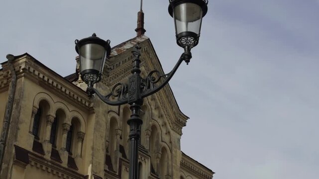 Historic yellow building facade with vintage wrought-iron street lamps in Saint Petersburg on an overcast day
