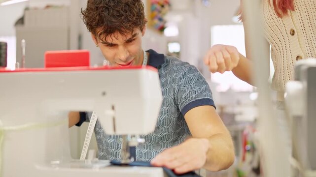 Male student learning sewing from teacher in a workshop