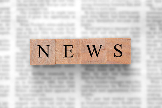 Newspaper background with wood blocks on top with the word news. Written press news media concept