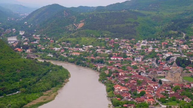 Beautiful aerial perspective of mtskheta, one of the oldest cities in georgia, showing the confluence of the mtkvari and aragvi rivers surrounding the historic town and its red-roofed houses