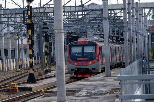 Solo, Indonesia - June 15, 2026: KAI Commuter train on the Yogyakarta-Solo route passing Solo Balapan Station with concrete catenary poles and overhead power lines.