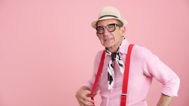Eccentric senior man with positive energy posing on a pink background