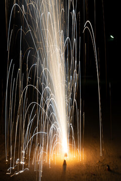 Slow shutter shot anar fountain firework during Diwali celebrations at night with trails of sparks with glowing flames and smoke.