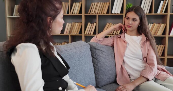 Therapist and teen girl counseling session conversation. A psychologist offers support in a private office, focusing on mentalhealth and stress relief. Concept of trust, care, communication.