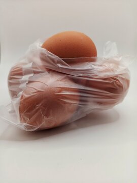 Brown chicken eggs packed inside a transparent plastic bag isolated on a white background. Daily grocery product representing food packaging, shopping, fresh ingredients, and household supplies.