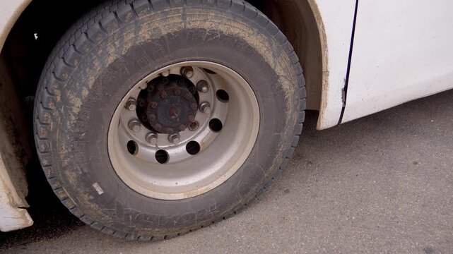 Close-up of a large bus wheel, slowly rolling on asphalt