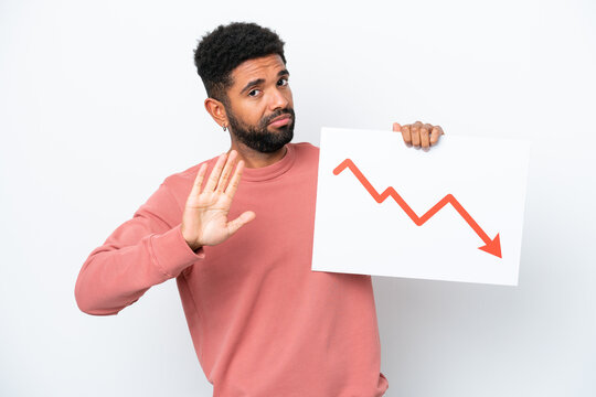 Young Brazilian man isolated on white background holding a sign with a decreasing statistics arrow symbol and doing stop sign