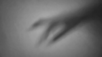 Obraz premium Shadow of a hand reaching out on a plain wall in low light
