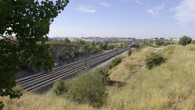 High speed passenger train traveling through the outskirts of Madrid on a sunny summer