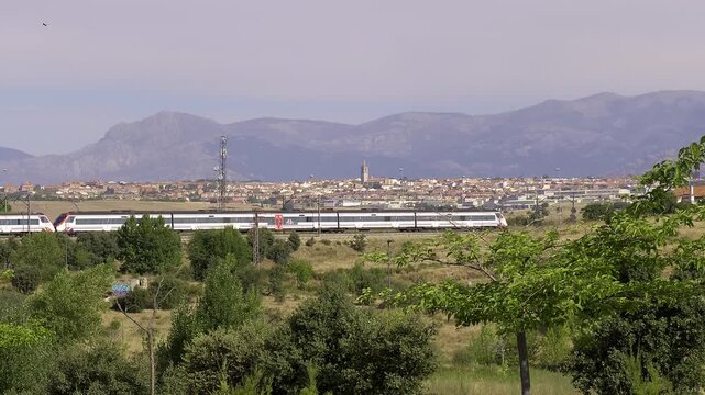 Commuter train crossing the Madrid outskirts with the Guadarrama Mountains in the background
