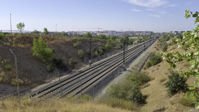 Modern high speed train passing along railway tracks with Madrid urban skyline in the background