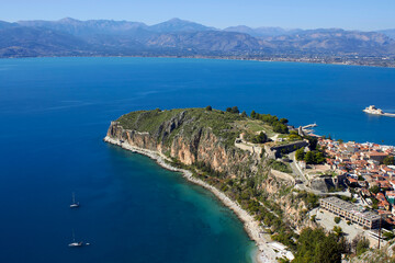 Obraz premium High angle view of Acronauplia fortress and Nafplio town overlooking the blue sea and mountains under a clear sky in Greece