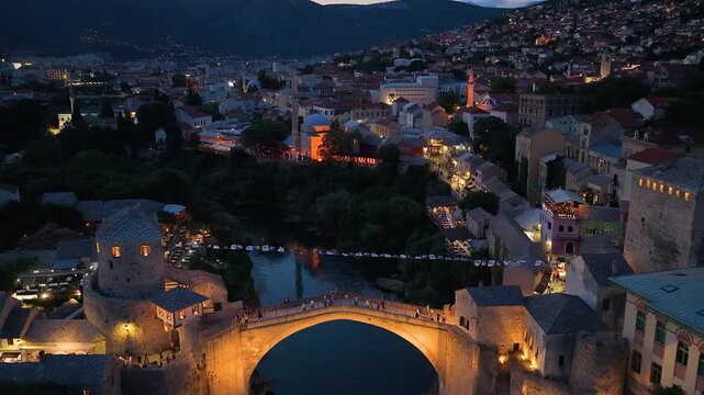 Mostar, Bosnia and Herzegovina - June 7, 2026: Drone flight above the illuminated Old Bridge toward the historic old town