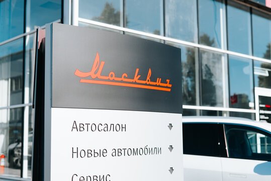 A car dealership sign moskvich is displayed outside a modern building in a busy urban area, clearly indicating services such as auto sales and service options Smolensk, Russia 07.17.2026