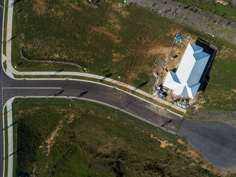 house under construction in new suburb with building rubbish inside fence