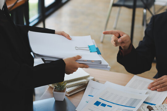 Accountant reviewing printed financial reports at messy office desk with calculator and sticky notes under soft window daylight for audit and corporate finance work