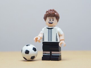 Fototapeta premium Indonesia - May 27, 2026 : Mini toy of action figure at outdoor with blur background. Miniature photography concept design. Minifigure of football player character with ball. World Cup America event.